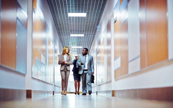 Business people walking down the office corridor and communicating